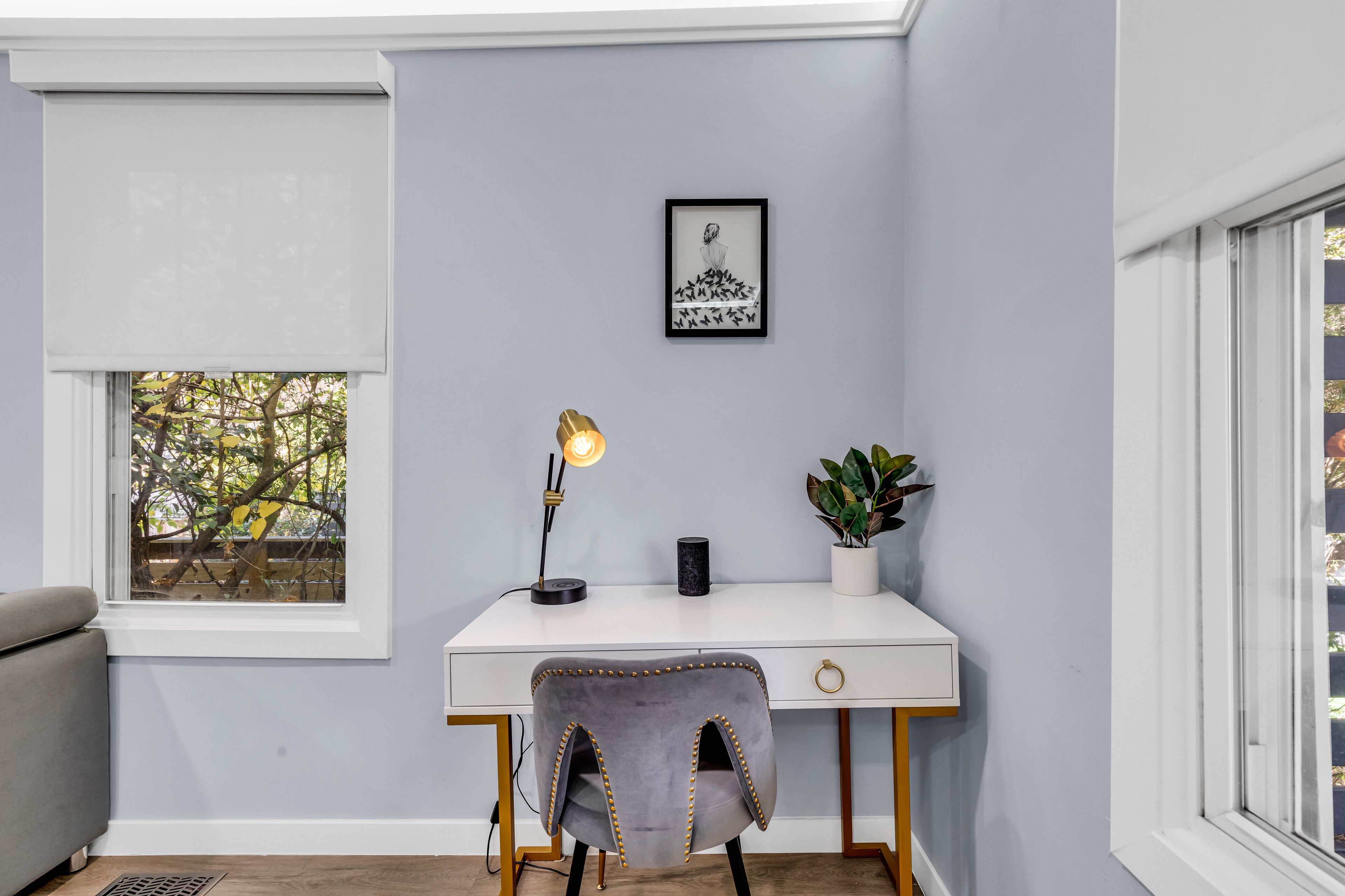 Un bureau avec une chaise, une lampe, un tableau encadré et une plante en pot.