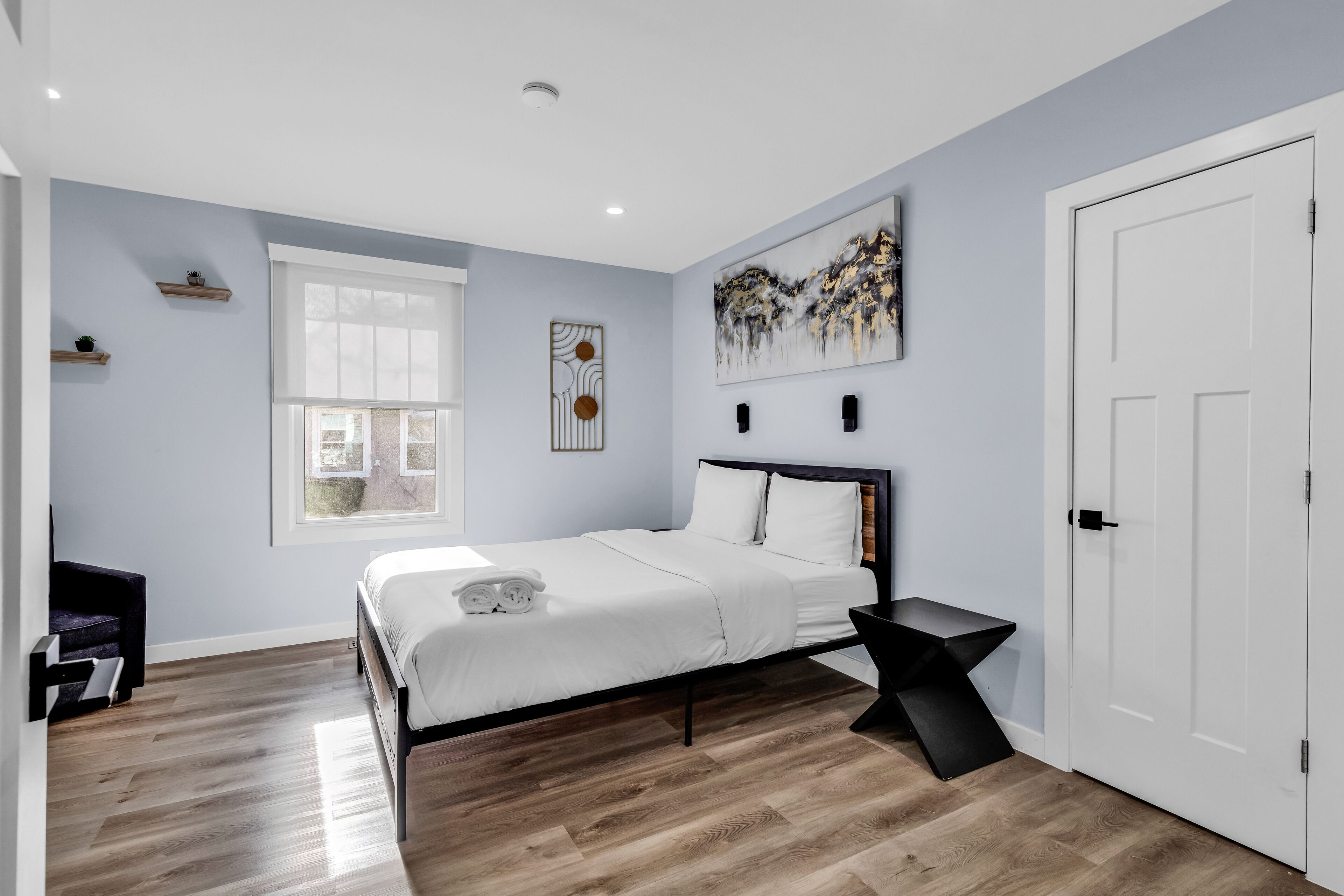 A modern bedroom with a bed, a bedside table, a window, and a door.
