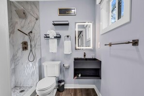 A modern bathroom with a shower, toilet, vanity, and a mirror with lights. - Luxury 3BR House in Charlotte (Charlotte)