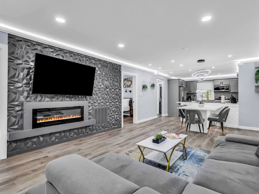 A modern living room with a fireplace, grey sofas, and a flat-screen TV.