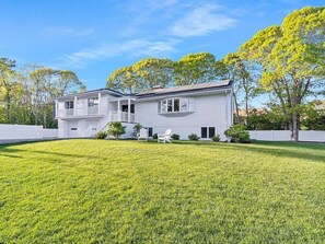 A two-story house with a front yard and a white picket fence.