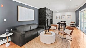 A modern living room with a black leather sofa, a round coffee table, and a stone accent wall.