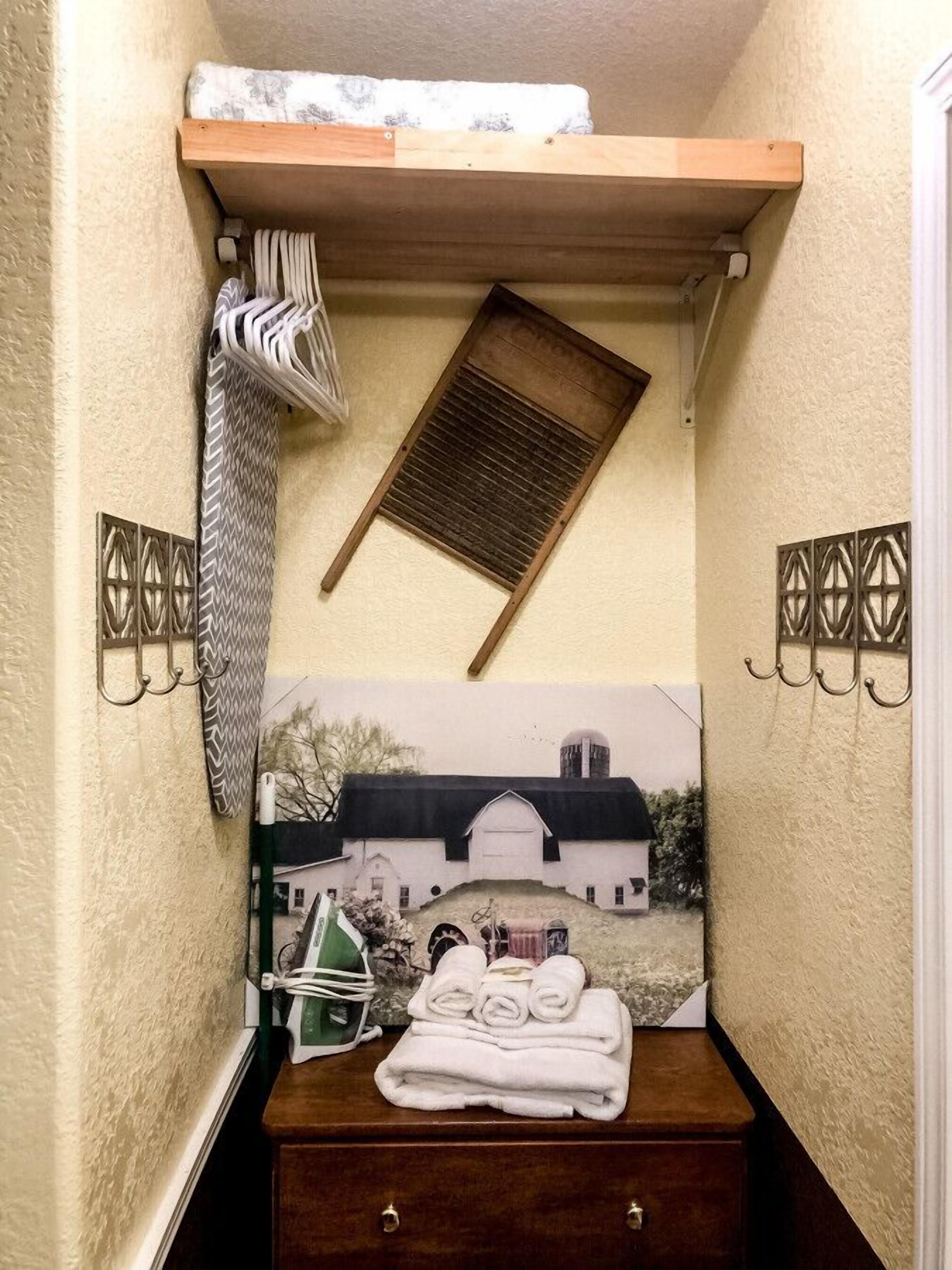 A small bathroom with a wooden shelf, a towel rack, a wall-mounted air purifier, and a decorative wall piece.