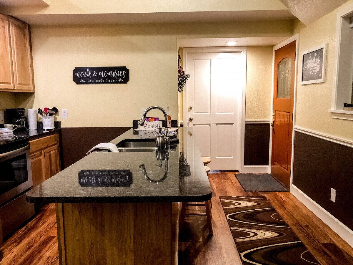 A kitchen with a central island, wooden cabinets, a coffee maker, and a sign that reads "meals & memories are made here."