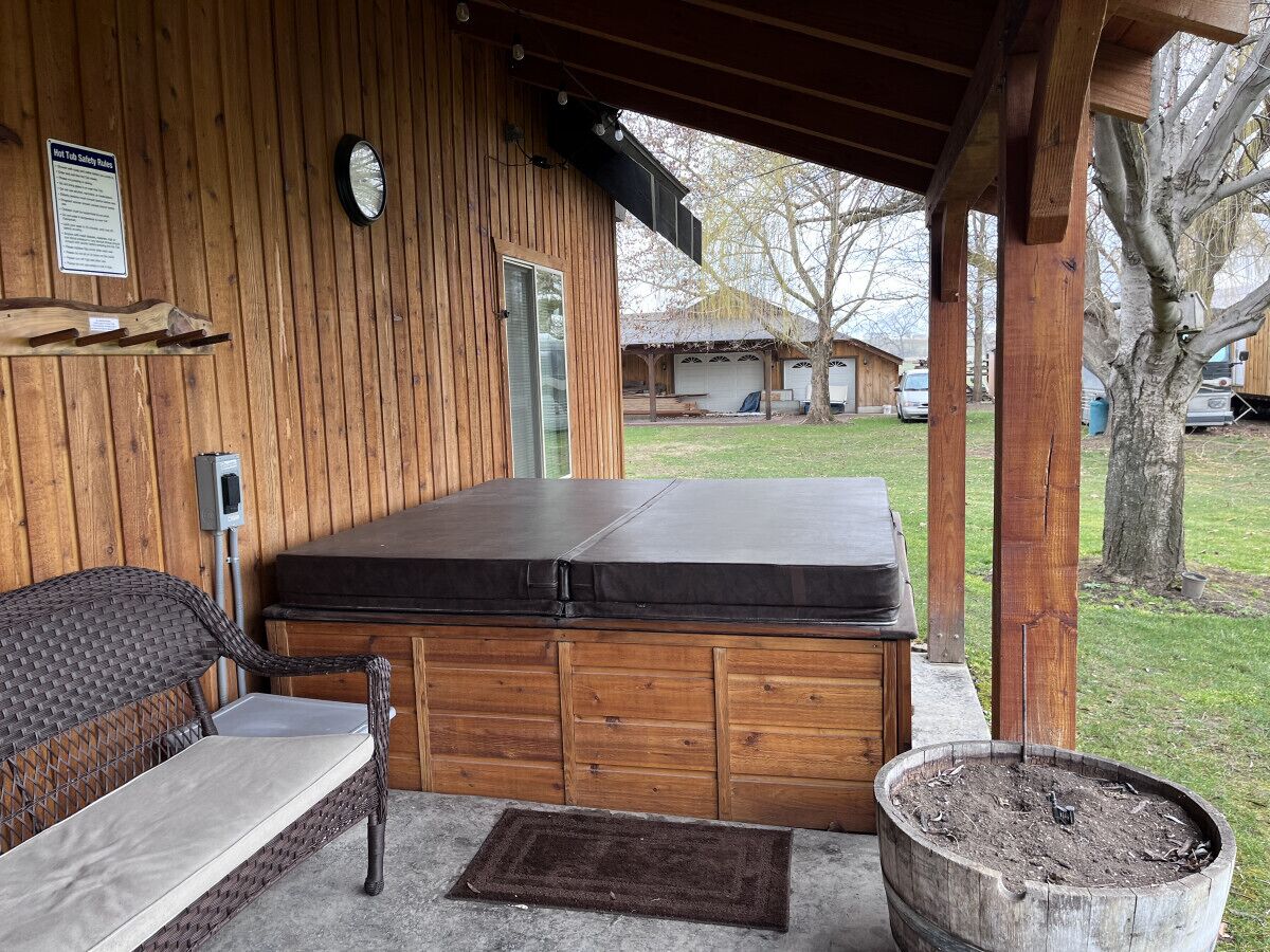 Een jacuzzi met een houten terras, een bankje en een klok aan de muur.
