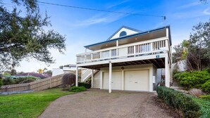 Une maison à deux étages avec un balcon, une véranda et un garage.