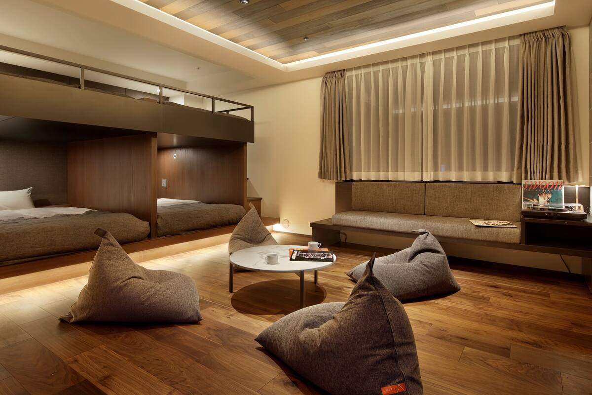 A modern living room with a bunk bed, a sofa, a coffee table, and bean bags.
