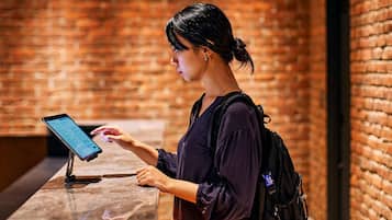 A person using a tablet at a counter with a brick wall background.