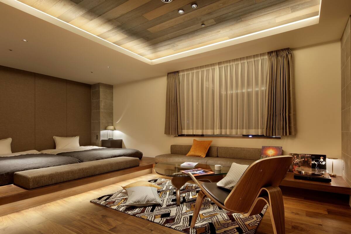 A modern hotel room with a large bed, a sofa, a coffee table, and a TV.