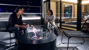 Two people seated at a table with a fire pit in the center, overlooking a cityscape at night. - 41PIECES Sapporo (Sapporo)