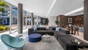 Un hall d’entrée spacieux, doté d’un grand canapé d’angle, d’une table basse ronde et d’un coin bar avec des tabourets.