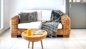 Ein modernes Wohnzimmer mit einem Korbsessel, einem runden Holztisch und einer hängenden Pendelleuchte.
