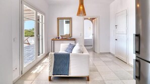 A modern bedroom with a bed, a bedside table, a mirror, and a view of a balcony. - The view 2 (Santa Maria Paros Νάουσα)