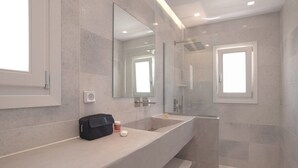 Un bagno moderno con uno specchio grande, un piano di lavoro lungo e uno spazio doccia.
