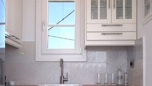 Una cucina moderna con mobili bianchi, un piano di lavoro in legno, forno integrato e una finestra sopra il lavello.