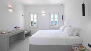 Camera da letto dal design minimalista con un letto, un comodino e due finestre vista mare.