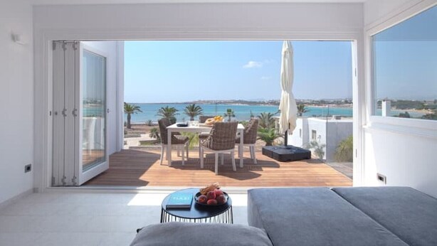 Un balcone con tavolo e sedie, un divano e vista sul mare.