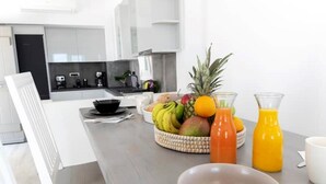 Eine moderne Küche mit einem Esstisch, gedeckt für das Frühstück, mit Obstschale, Glas Orangensaft und weißer Tasse.