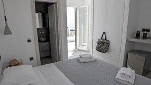 Ein Hotelzimmer mit Bett, Koffer, Hut, Handtuch, Tasche und einer Kaffeemaschine.