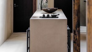 A modern kitchen with a central island, pendant lights, and a view of a garden through a window. - Maana Kiyomizu (Kyoto)