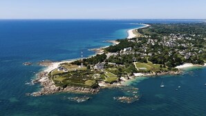 An aerial view of a coastal property with a large house surrounded by landscaped gardens, a beach, and a rocky shoreline. - Exceptional apartment - Seafront (Fouesnant)