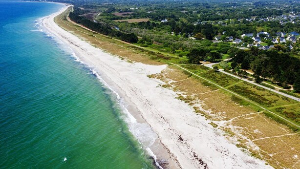 An aerial view of a coastal area with a beach, residential buildings, and green spaces. - Exceptional apartment - Seafront (Fouesnant)