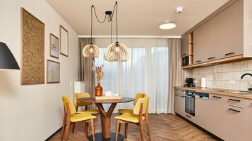 Una cocina moderna con armarios de madera, una zona de comedor con una mesa redonda y sillas amarillas, e iluminación colgante.