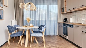 Eine moderne Küche mit Holdekor, einem eingebauten Backofen und einem Geschirrspüler. Es gibt einen Essbereich mit einem runden Tisch und vier Stühlen.