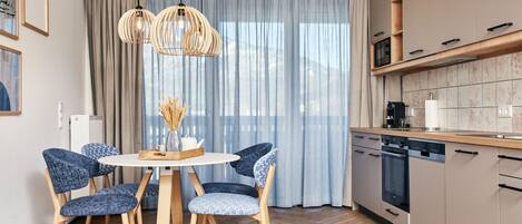 A modern kitchen with wooden cabinets, a built-in oven, and a dishwasher. There is a dining area with a round table and four chairs.