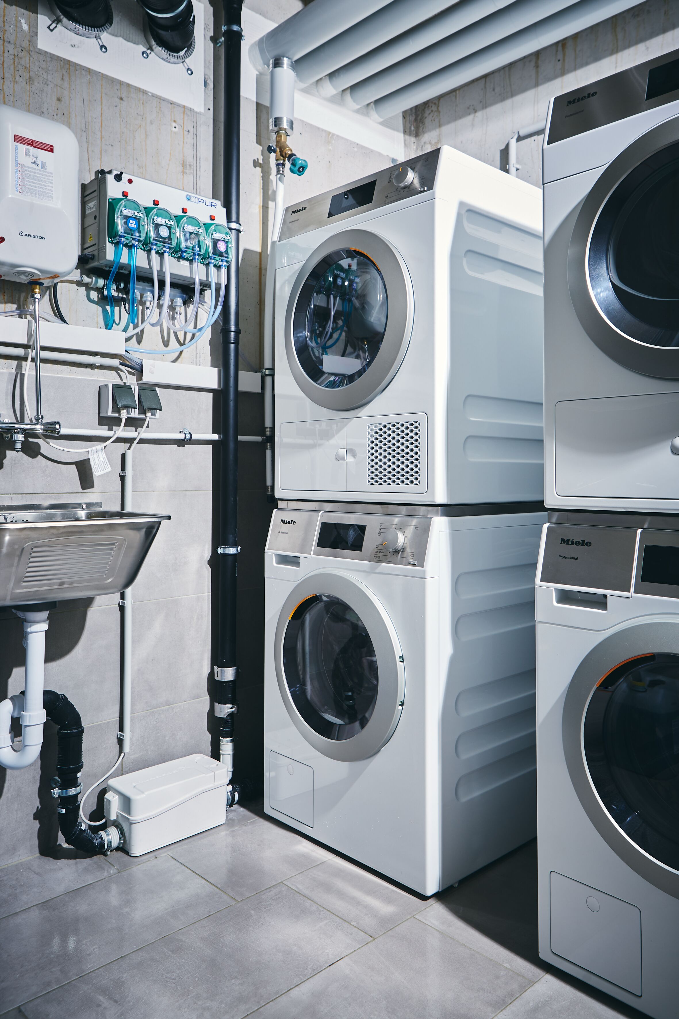 A laundry facility with multiple washing machines, a water heater, and a sink.