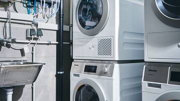 A laundry facility with multiple washing machines, a water heater, and a sink.