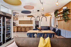 Un restaurante moderno con barra de madera, asientos tapizados en azul y varios candelabros colgantes.