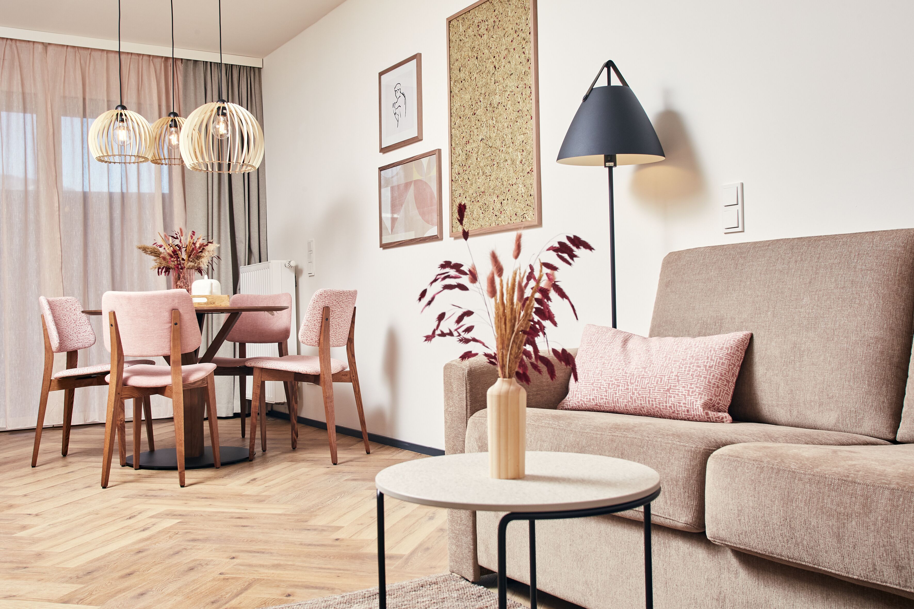 Een moderne woonkamer met een ronde salontafel, een bank, een eettafel met stoelen en hanglampen.