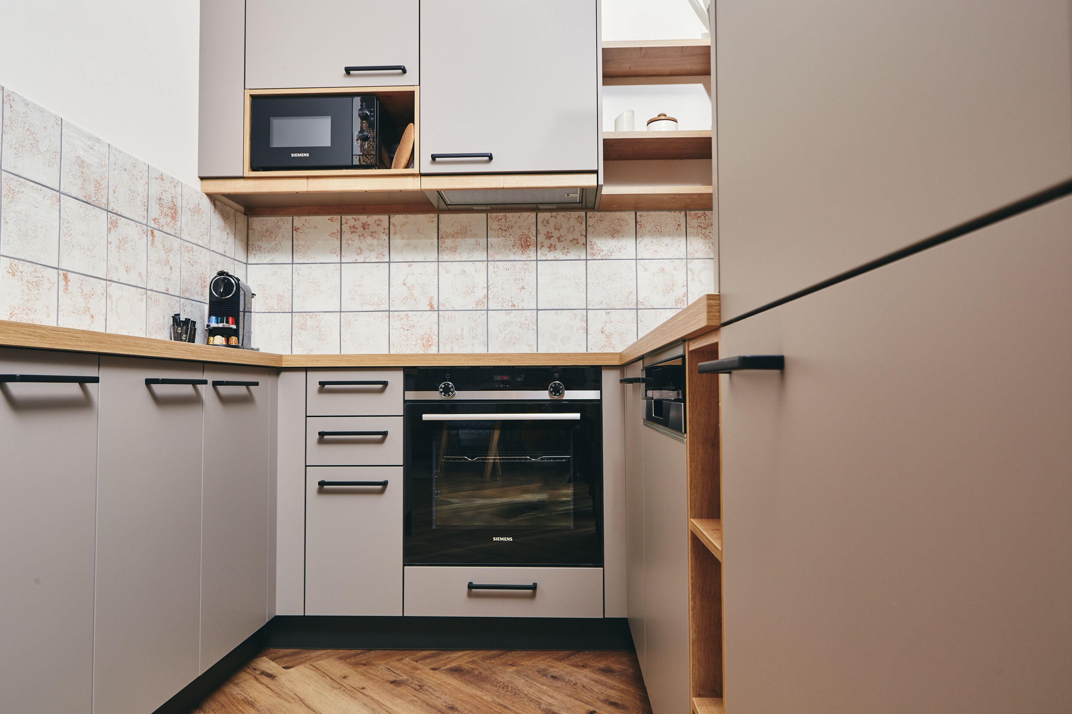 A compact kitchen with white cabinets, a built-in oven, and a microwave.