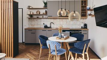 A modern kitchen with wooden cabinets, a central island, and blue patterned chairs.