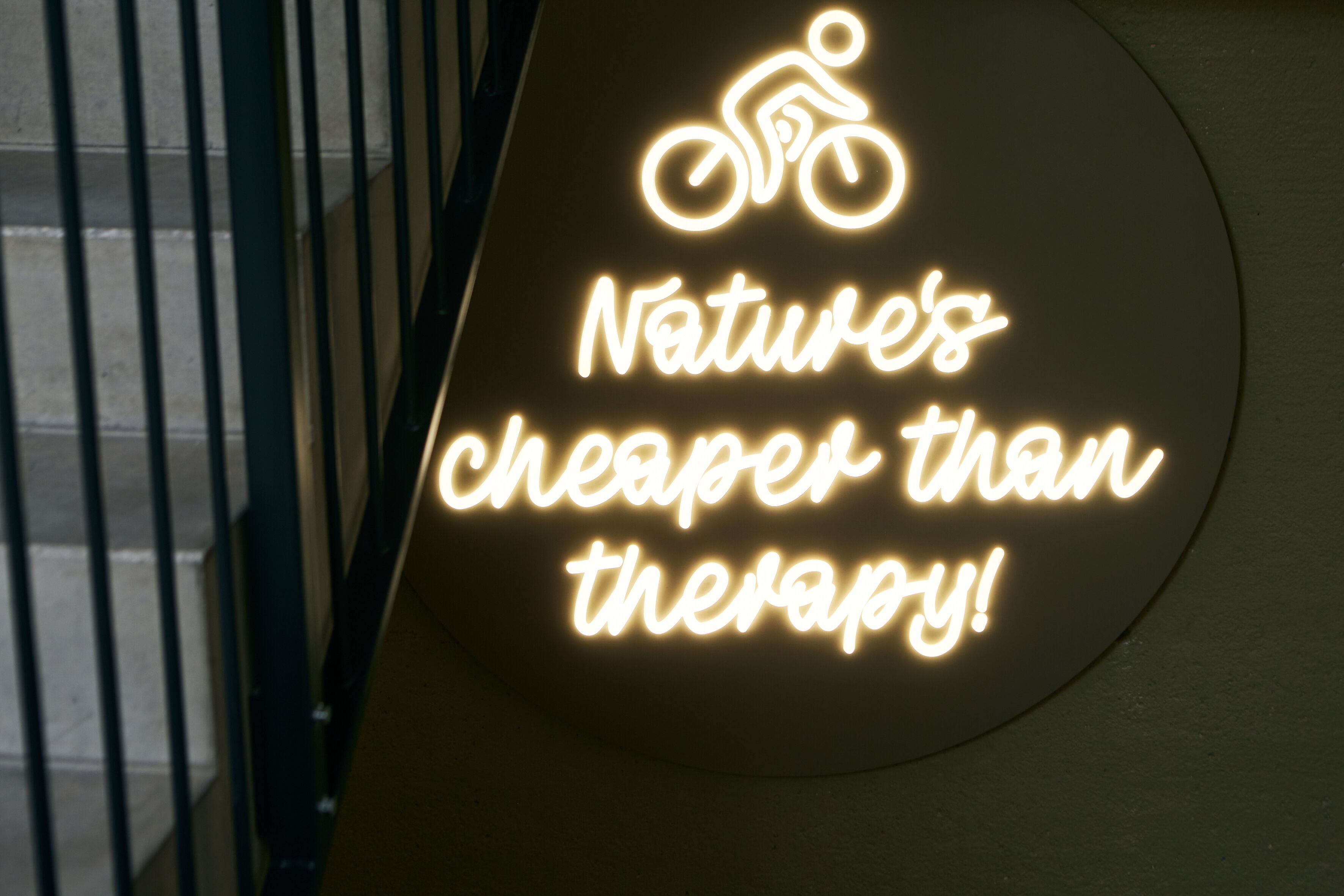 Un neon con un simbolo di bicicletta e il testo "Nature's cheaper than therapy!"
