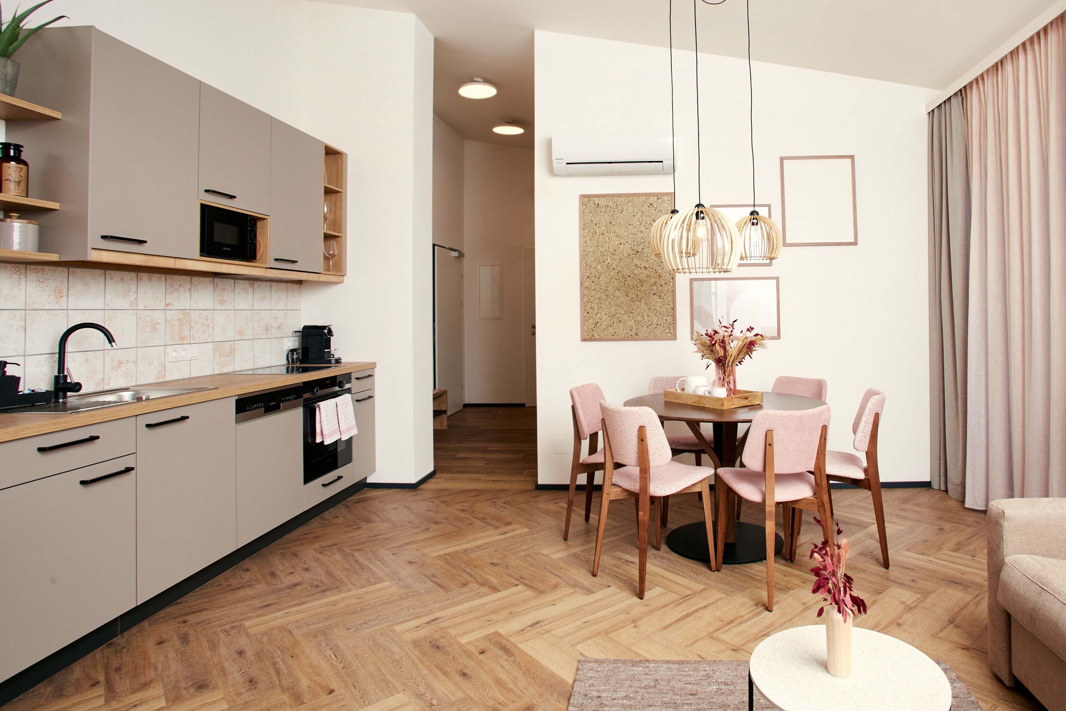Una cocina moderna con electrodomésticos integrados, un comedor con mesa redonda y sillas, y una sala de estar con sofá y mesa de centro.