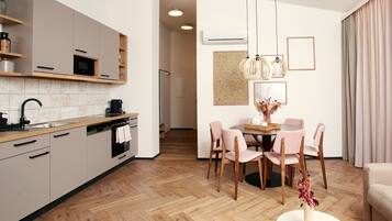 Eine moderne Küche mit eingebauten Geräten, ein Essbereich mit rundem Tisch und Stühlen sowie ein Wohnbereich mit Sofa und Couchtisch.