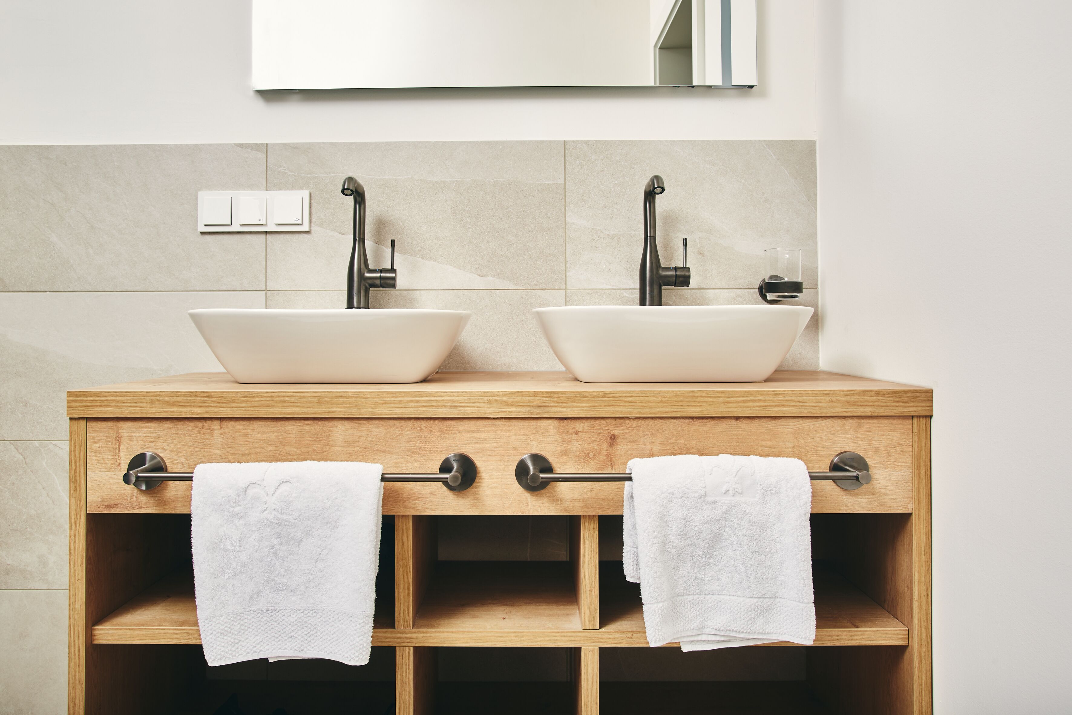 A wooden vanity with two white sinks and a mirror above.