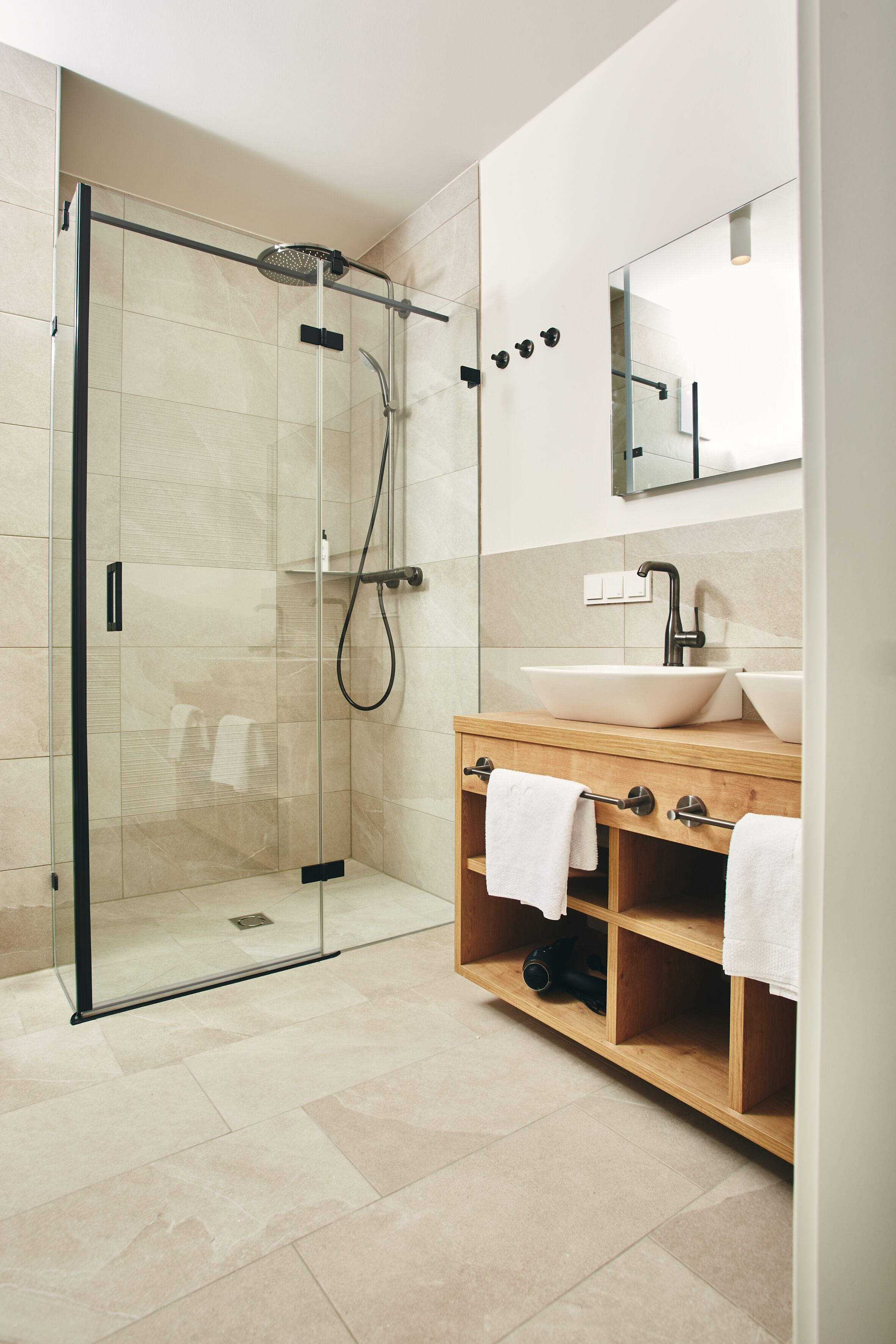 A modern bathroom with a glass-enclosed shower, a wooden vanity with a sink, and a mirror above the vanity.