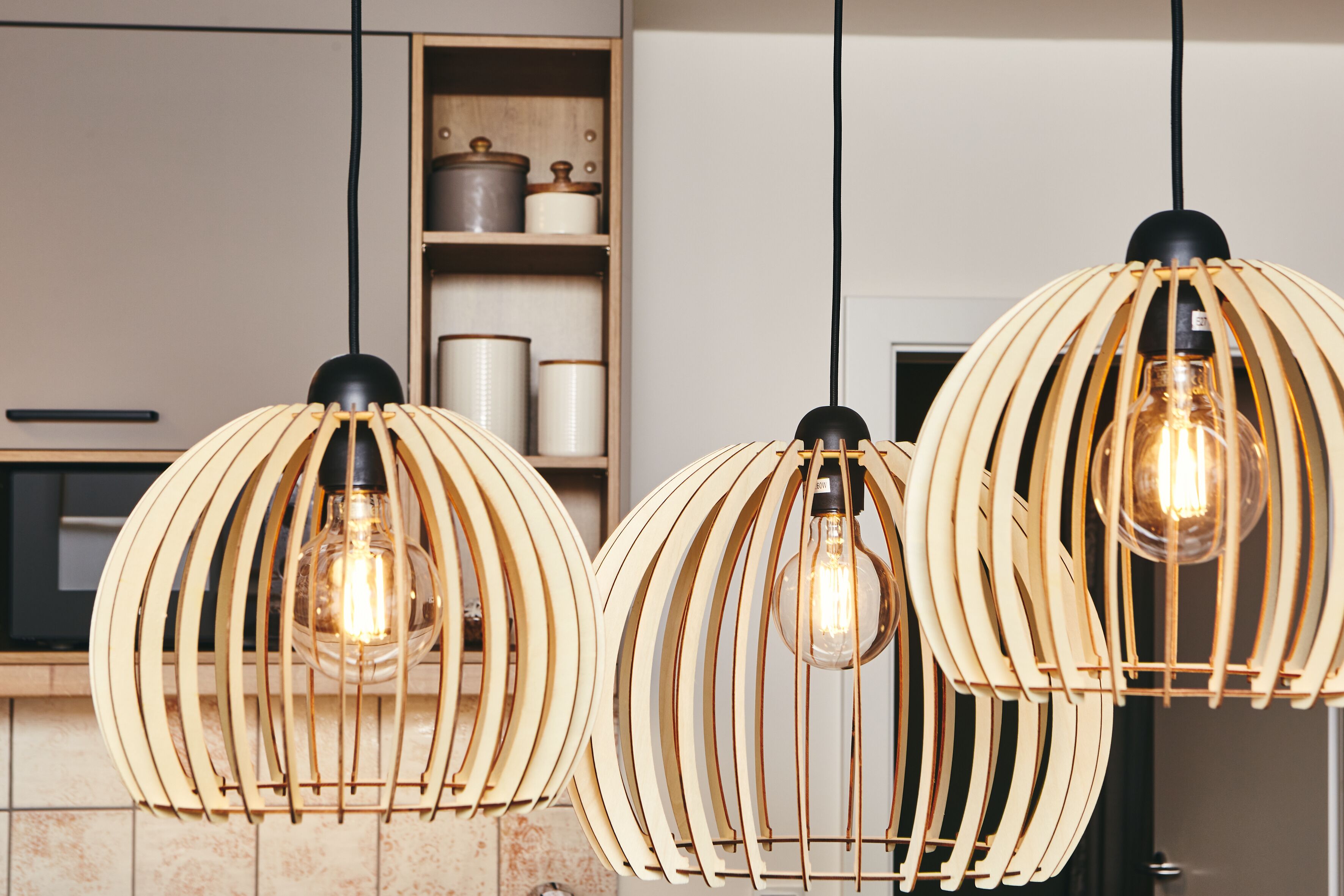 Una cocina con lámparas colgantes de madera y muebles de cocina modernos.