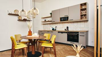 A modern kitchen with wooden cabinets, a microwave, and a dining area with yellow chairs and a round table.