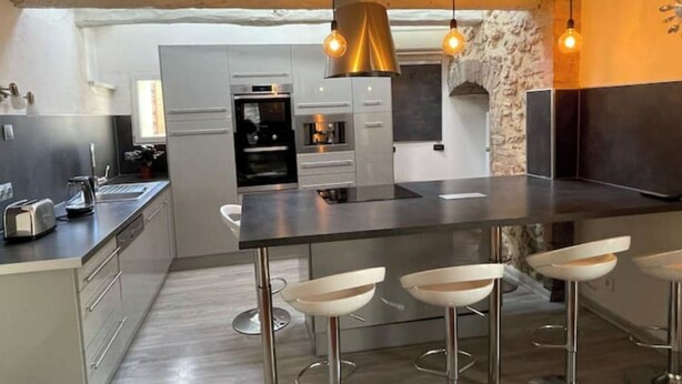 Una cocina moderna con una isla central, taburetes de bar e iluminación colgante.