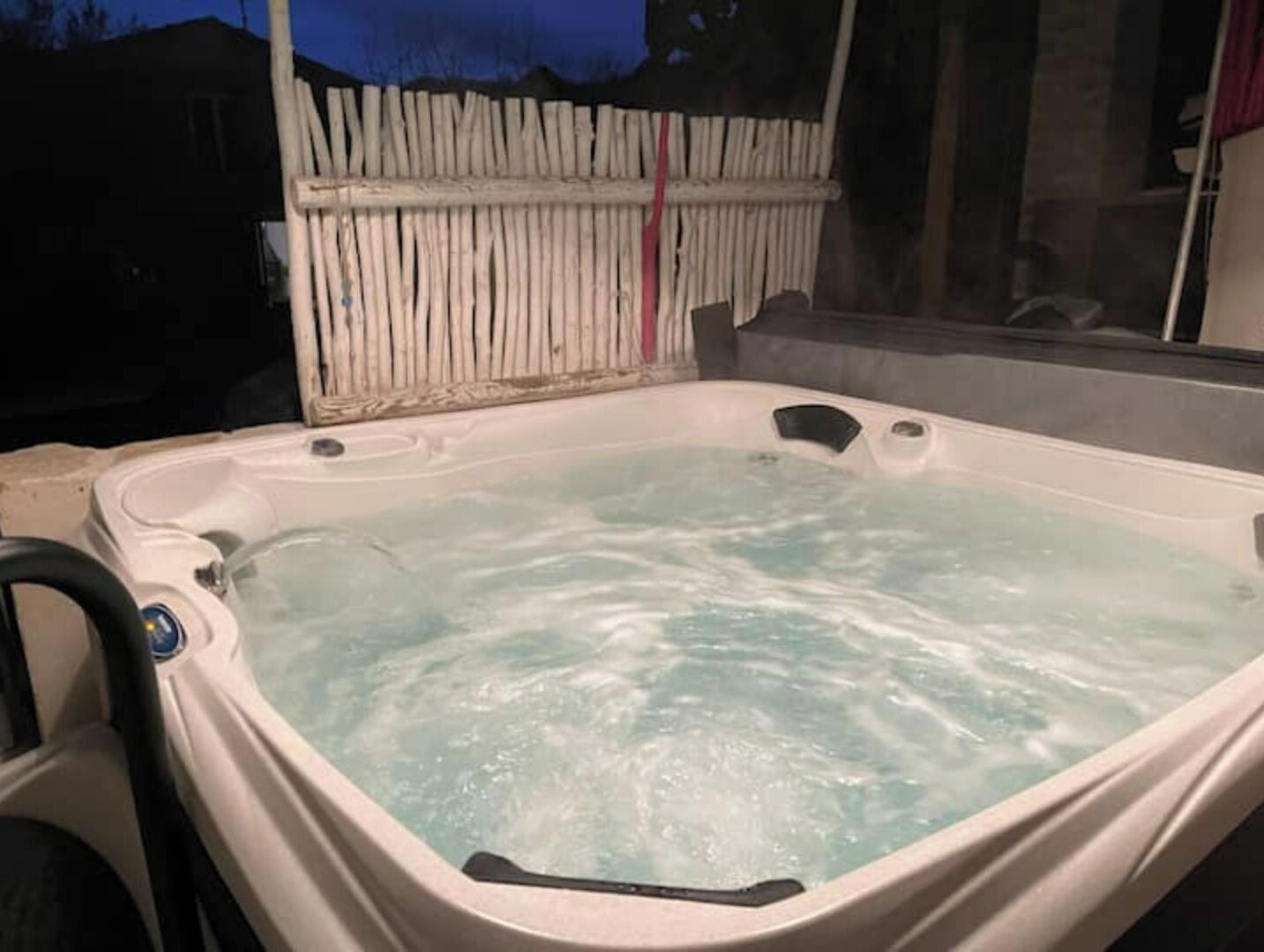 Ein Whirlpool mit einem Holzzaun im Hintergrund.