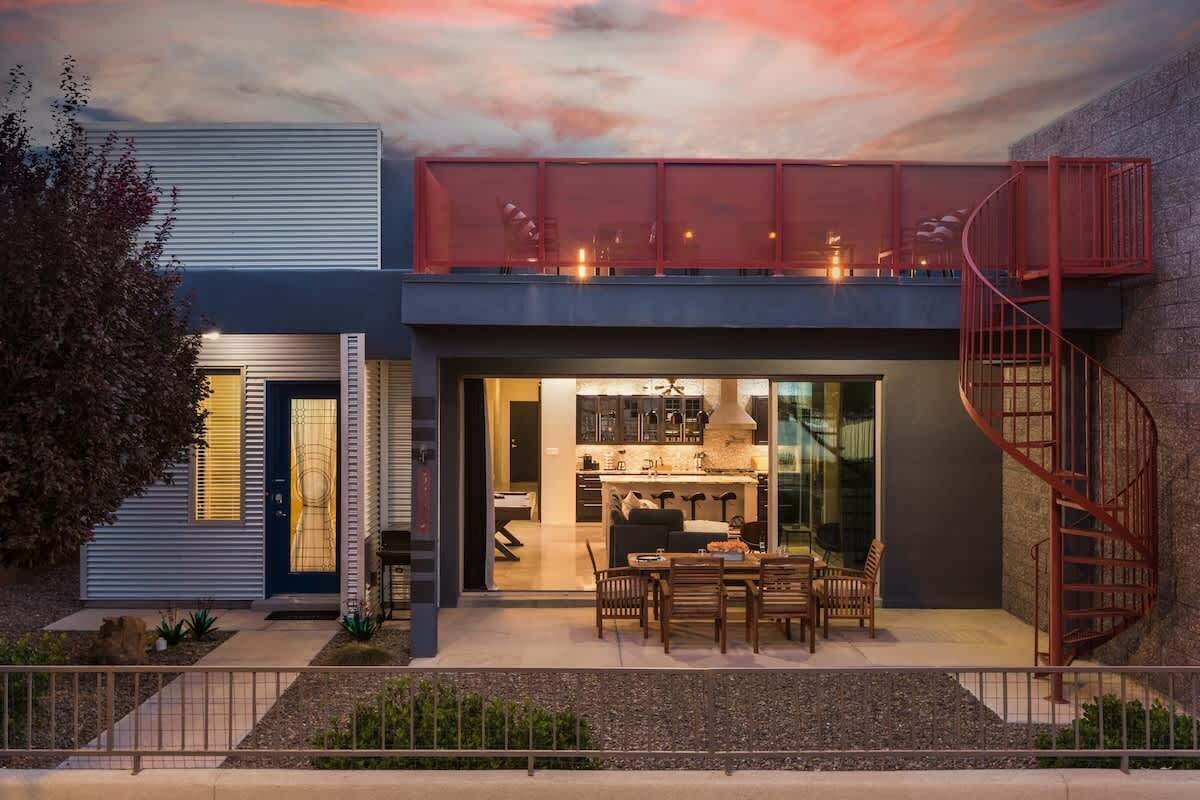 A modern house with a dining area, kitchen, and a spiral staircase.
