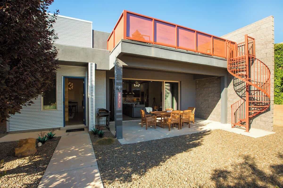 A modern house with a covered patio, a spiral staircase, and a visible kitchen area.