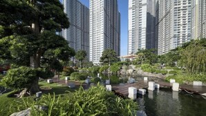 A serene park with a pond, surrounded by tall residential buildings.