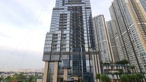 A high-rise building with a modern glass facade, surrounded by other tall buildings and greenery.