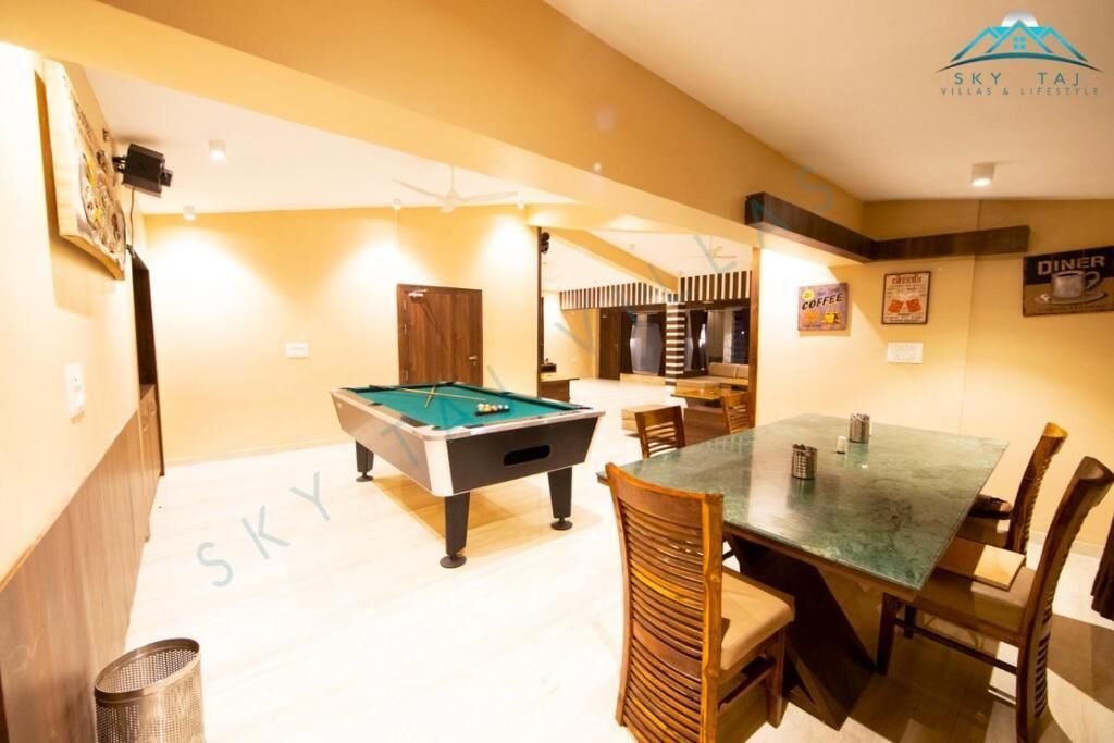 A pool table in a room with a dining table and chairs.