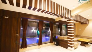 A modern interior with a pool area, wooden paneling, and a staircase. - Sky Taj Villa 5 BHK (Igatpuri)